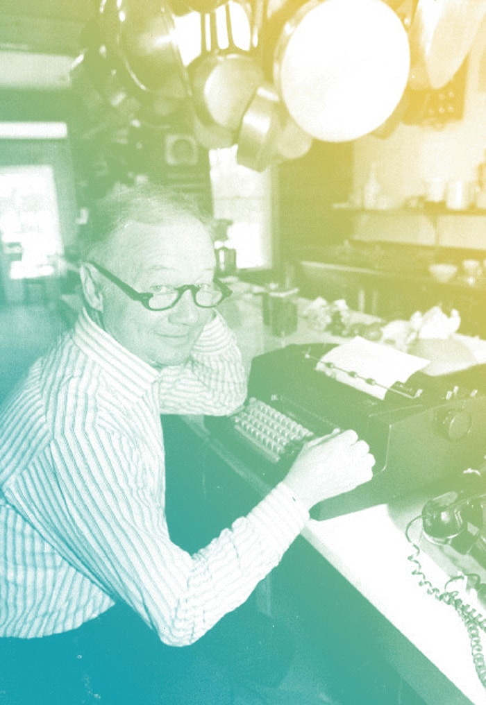 Craig Claiborne seated in a diner at a typewriter.