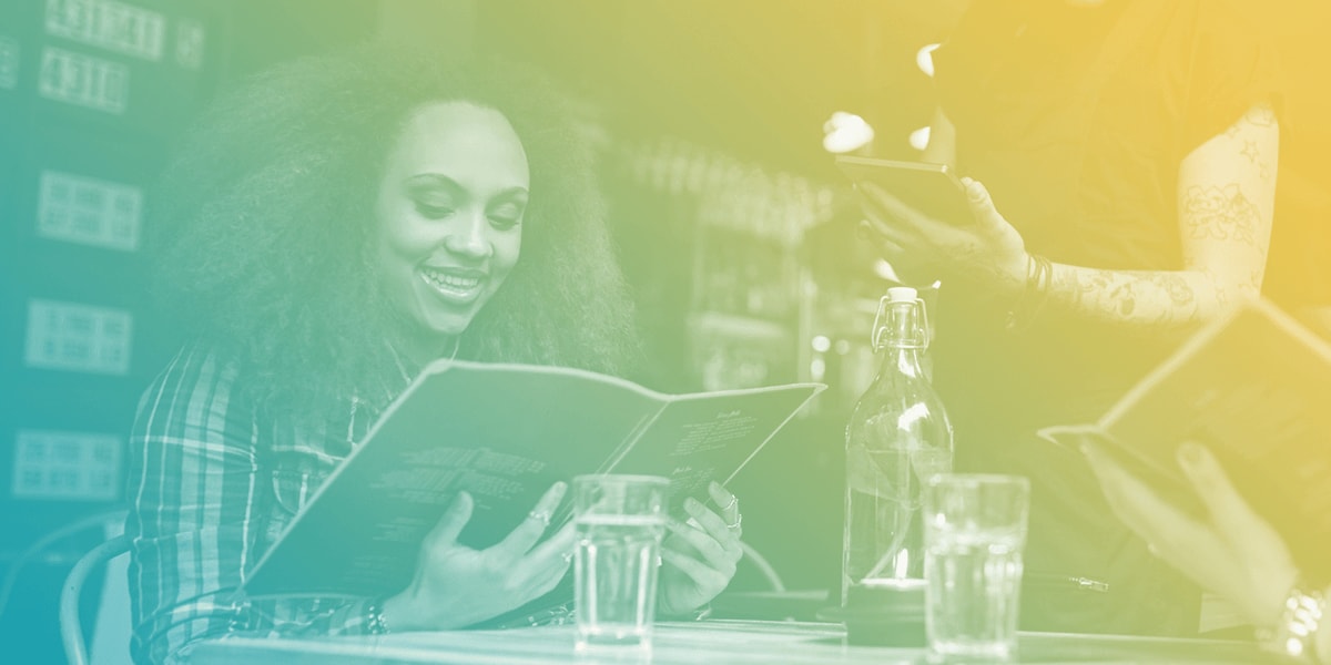 A woman ordering from a menu to her waiter.