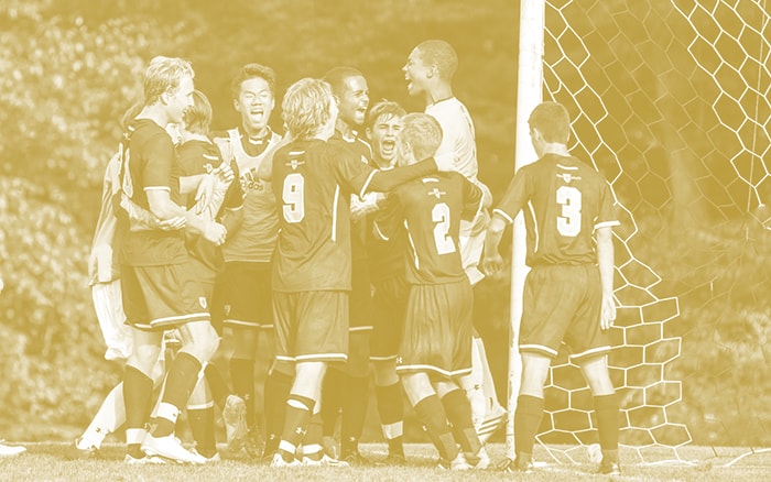 A junior soccer team celebrating victory with their coach.